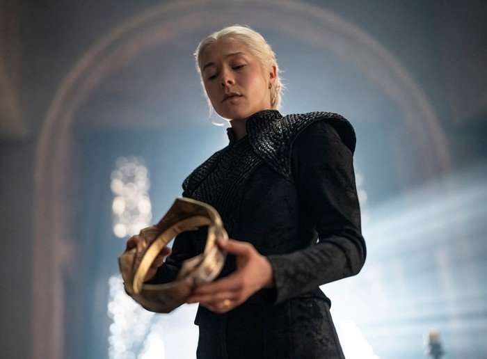 Emma D'Arcy as Queen Rhaenyra Targaryen holding a golden crown in House of the Dragon season 3.