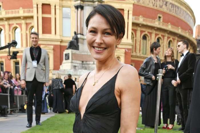 Emma Willis stood in front of the Royal Albert Hall, smiling ahead. She is wearing a black dress.