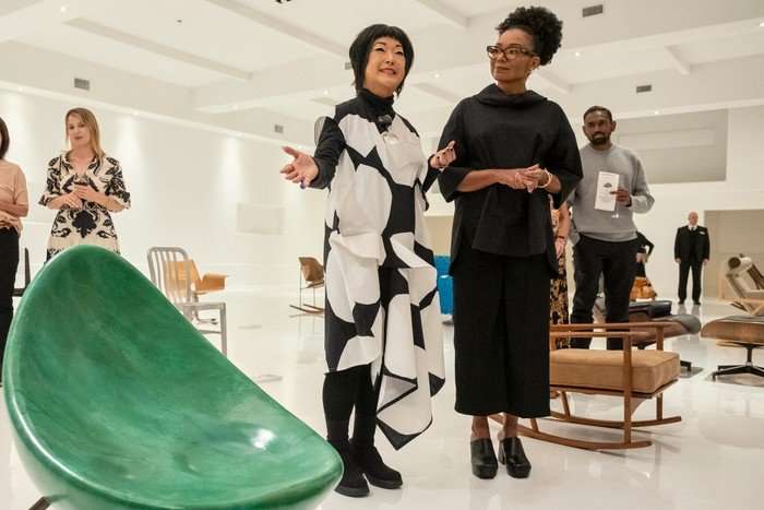 Fumi standing next to a customer in the showroom presenting a green egg-shaped chair