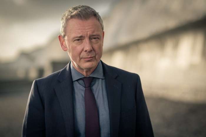 John Simm as DS Roy Grace in Grace, wearing a suit and looking at the camera.