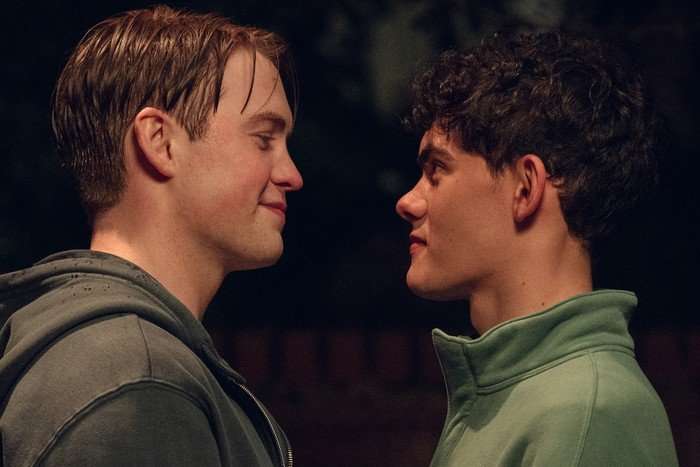 Nick Nelson and Charlie Spring standing close together and smiling at each other