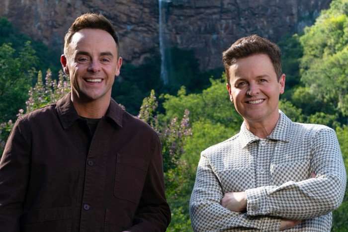 Ant and Dec stood next to each other with a forest backdrop, smiling ahead.