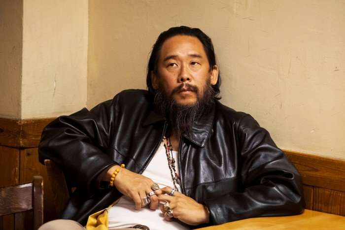 isaac sat at a table with his back against the wall