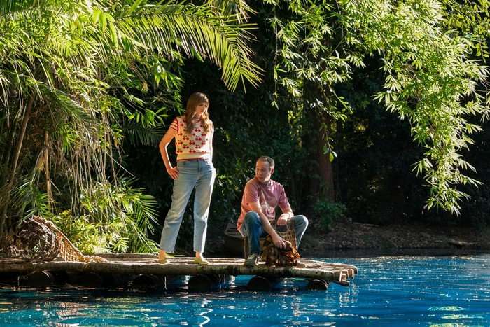 Lauren Lapkus and Kevin Sussman star in Stuart Fails to Save the Universe; they are on the edge of a blue lake in a leafy green forest