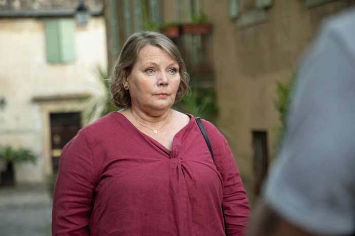 Joanna Scanlan as Sarah standing outside on a street, looking at someone who approaches her.