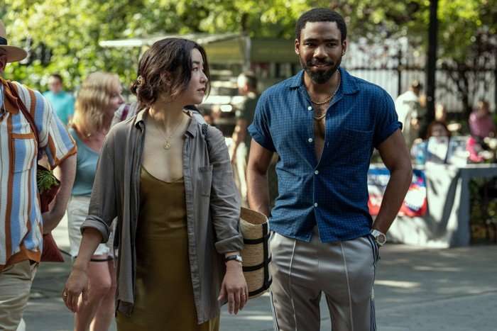 Maya Erskine and Donald Glover walking together through a market