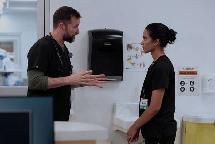Noah Wyle and Supriya Ganesh in The Pitt, talking to one another in a hospital.