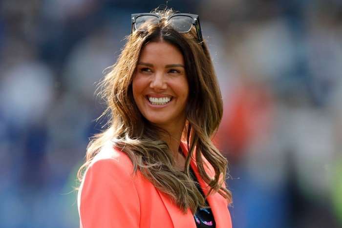 Rebekah Vardy wearing a pink blazer, smiling ahead with sunglasses on her head.