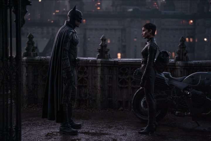 Batman stands across from Catwoman and looks at her.