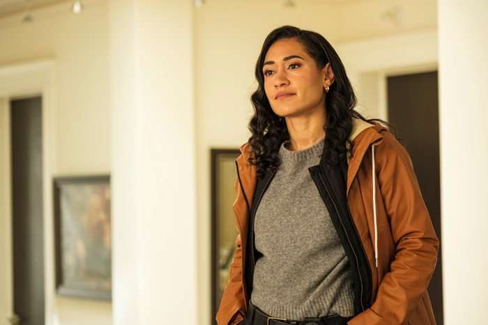 Jos&eacute;phine Jobert in Saint-Pierre standing in a grey t-shirt and hooded brown jacket, with her hands in her pockets, smiling.