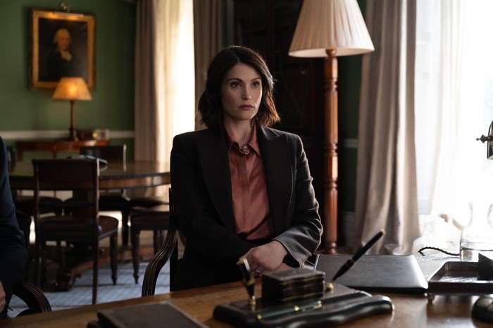 Gemma Arterton as Kate in Secret Service, sat in front of a desk in an office.