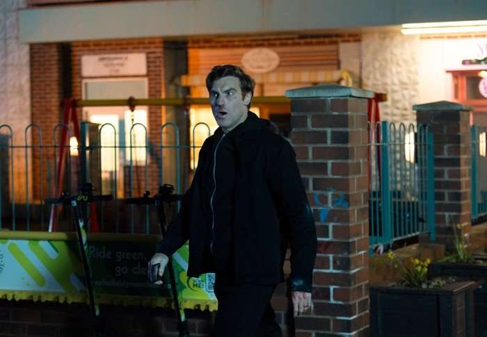 Theo stood in the precinct in a scene from Coronation Street