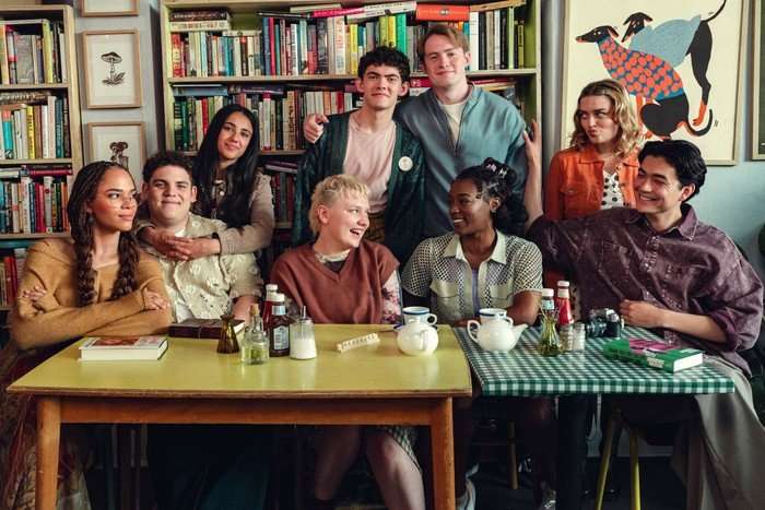 A group of teenagers pose together in a classroom in front of a table.