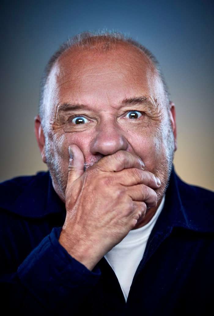 Bob Mortimer looking ahead with one hand covering his mouth.