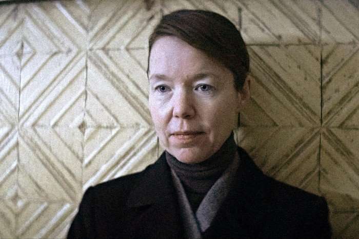 15_Star_City_Photo_010201 Anna Maxwell Martin as KGB agent Lyudmilla in Star City. She stands against a textured tiled wall and wears a black jacket and grey turtleneck, giving a steely glare to the outside world.
