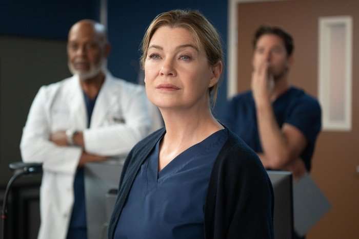 Ellen Pompeo as Meredith Grey in Grey's Anatomy in scrubs with other medical staff behind
