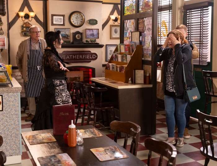Roy and Nina stand proudly in the cafe, beside Fiz and Chesney, who are covering their eyes in Coronation Street