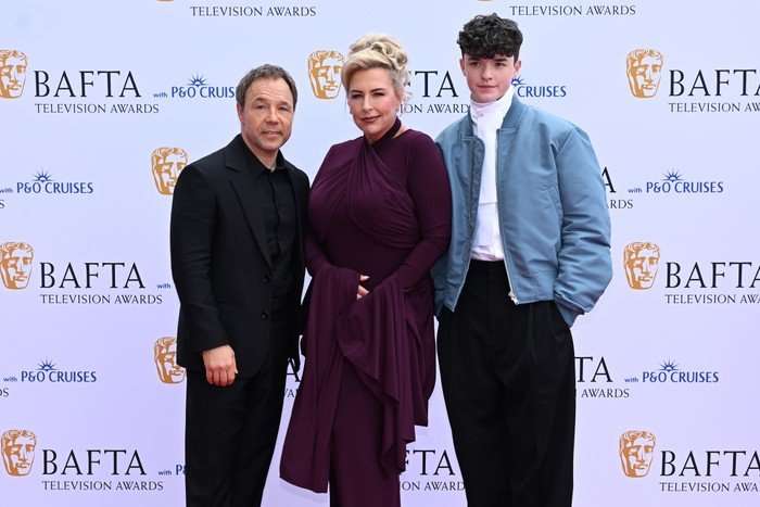 Stephen Graham, Hannah Walters and Owen Cooper stand a group on the red carpet looking ahead.