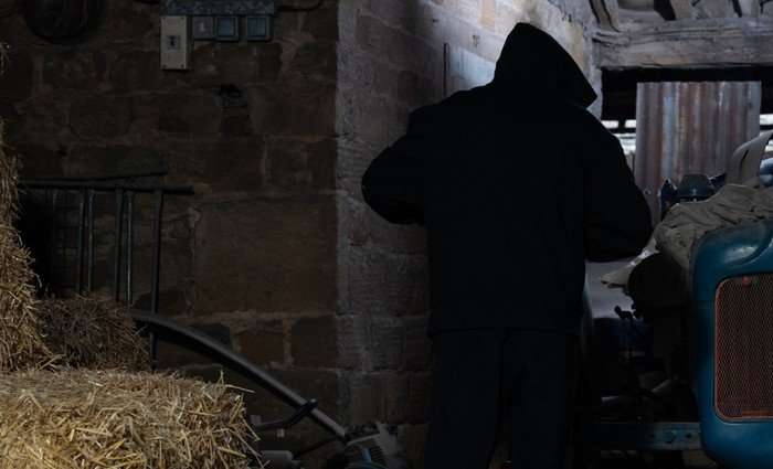 A hooded figure stands in a barn in Emmerdale