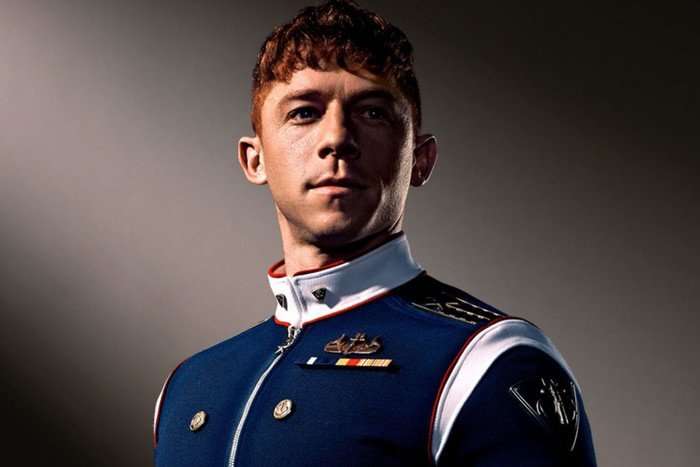 A man with red hair poses in a blue uniform with veteran badges on his lapel