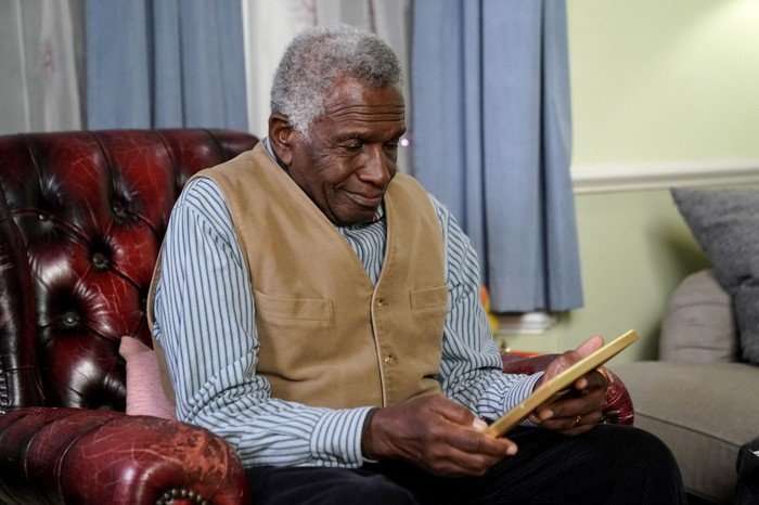 551409,TITLE:Eastenders Patrick smiles at a photo in a scene from EastEnders