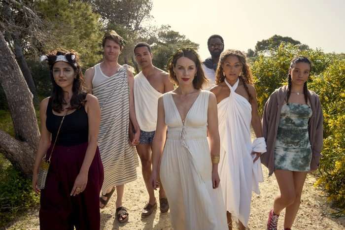 554910,TITLE:Two Weeks In August Leila Farzad as Nat, Hugh Skinner as Jacob, Dylan Brady as Will, Jessica Raine as Zoe, Nicholas Pinnock as Solomon, Antonia Thomas as Jess and Maria Almeida as Avery in Two Weeks in August, wearing white dresses and costumes, walking through a street in Greece together.