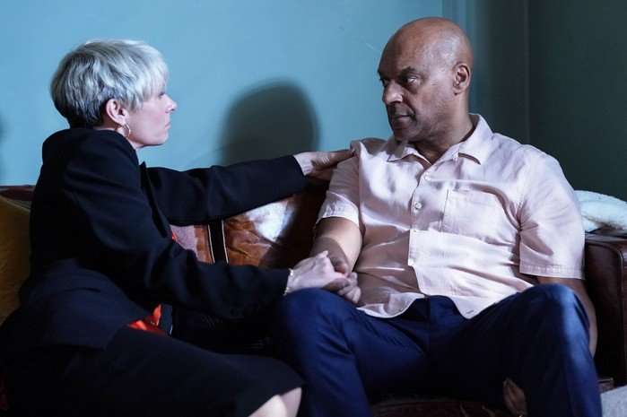 George and Nicola chat on a sofa in a scene from EastEnders