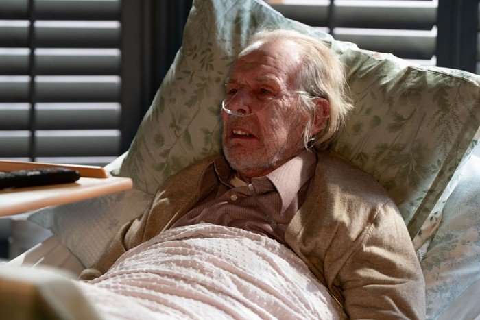 Eddie lies in a hospital bed in Nicola's living room in EastEnders