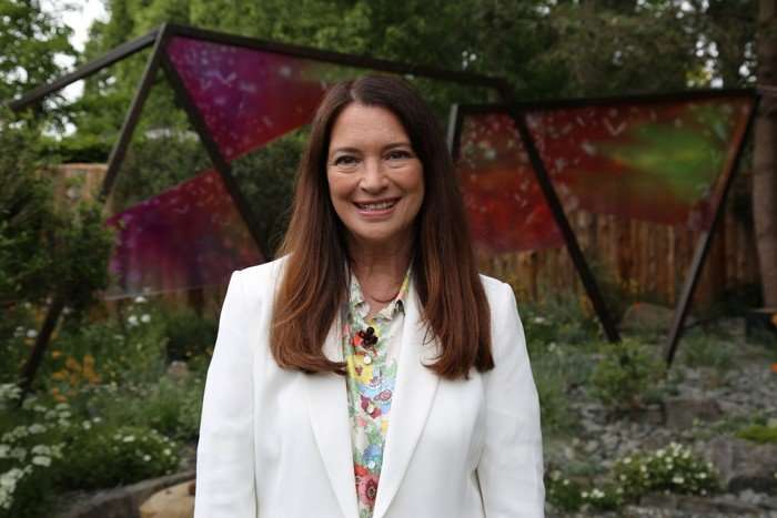 Rachel de Thame smiling ahead wearing a floral shirt and white blazer.