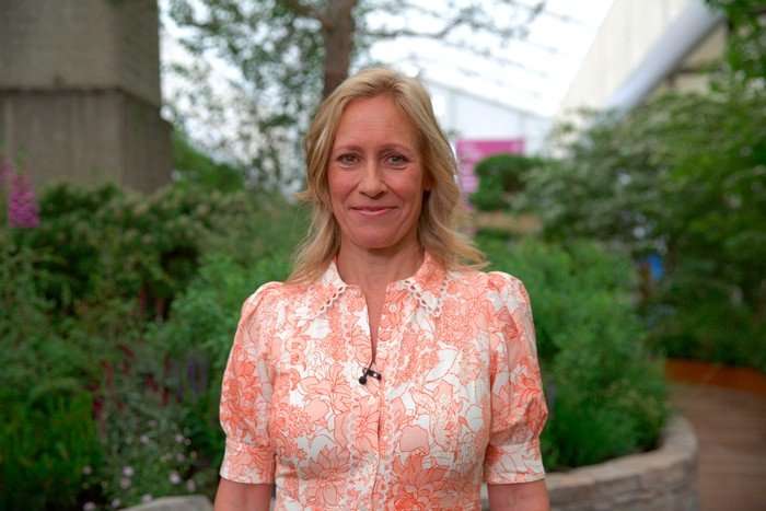 Sophie Raworth stood wearing a white and orange floral dress, smiling.