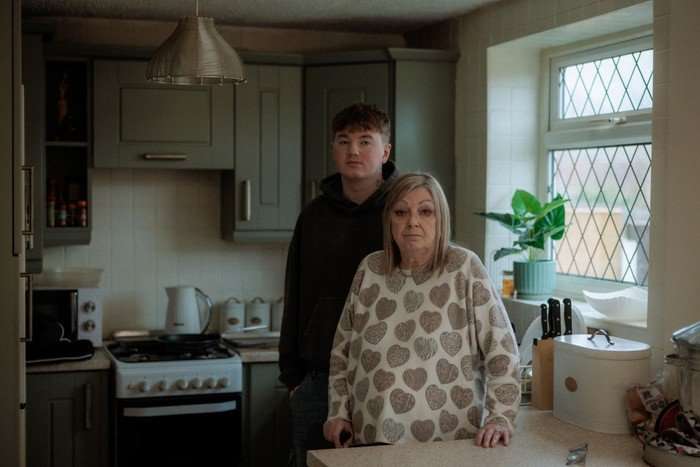 Alex Batty and his grandmother Susan stood one behind the other in a kitchen.