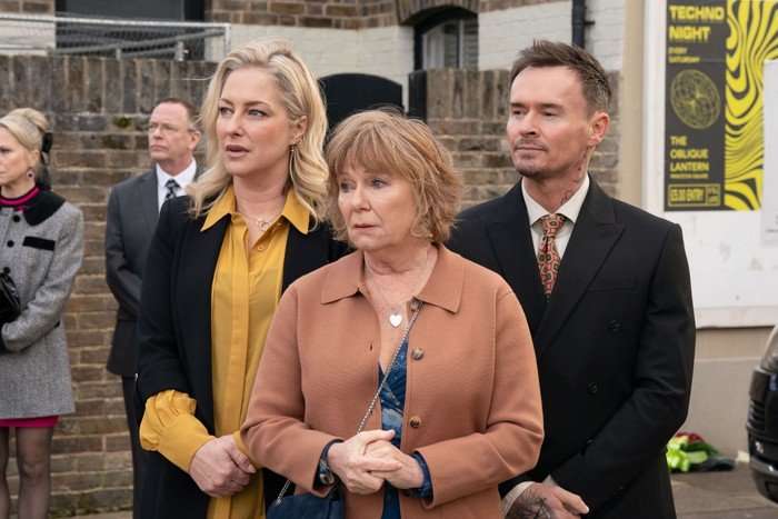 Clare, Julie and Josh watch Nigel's funeral procession, with Ian stood in the background, in a scene from EastEnders