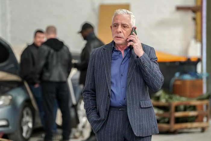 Russell on the phone, with his cronies stood behind him, in a scene from EastEnders