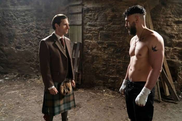 Richard Gadd and Jamie Bell in Half Man. Bell is wearing a suit with a kilt and Gadd is shirtless with boxing wraps around his hands. They are stood in a barn and looking at one another intensely.