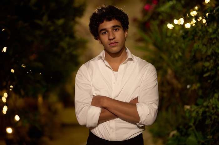 561632,TITLE:Two Weeks In August Khalil Gharbia as Jon in Two Weeks in August, stood outside at night, wearing a white shirt and black trousers and with his arms crossed.
