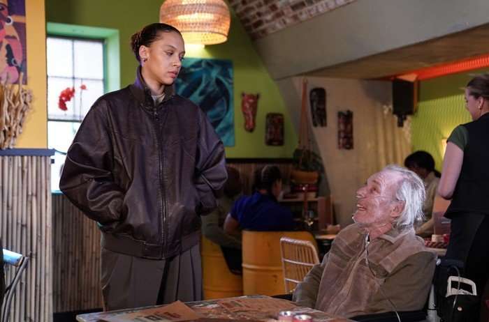 Gina stands over Eddie in Knight Fusion in a scene from EastEnders