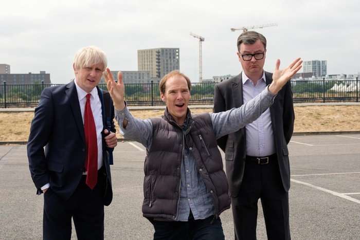 Brexit Richard Goulding as Boris Johnson, Benedict Cumberbatch as Dominic Cummings and Oliver Maltman as Michael Gove in Brexit: The Uncivil War, stood outside. Cummings is in the middle, with his arms outstretched, smiling.