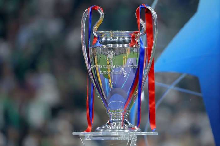 The Champions League trophy, with blue and red ribbons, on a glass plinth.