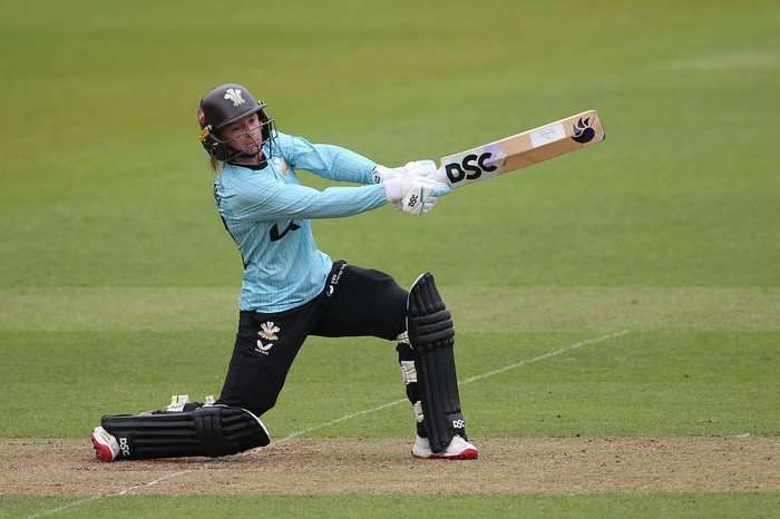Danni Wyatt, in blue and black Surrey kit with full batting pads and a helmet on, hits a cover drive.
