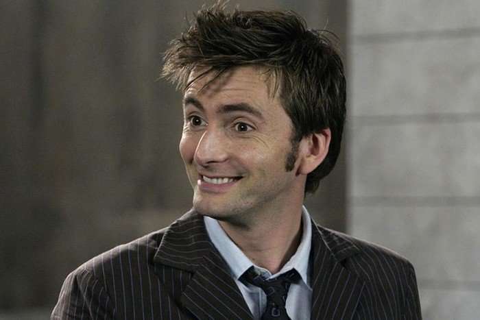 David Tennant as the Tenth Doctor, wearing his brown suit and smiling