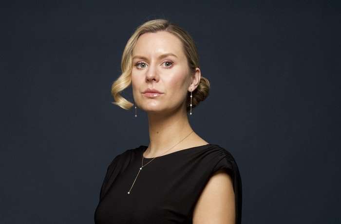 Olivia Bromley poses with her arms in front of her wearing a black dress with a stern expressoin.