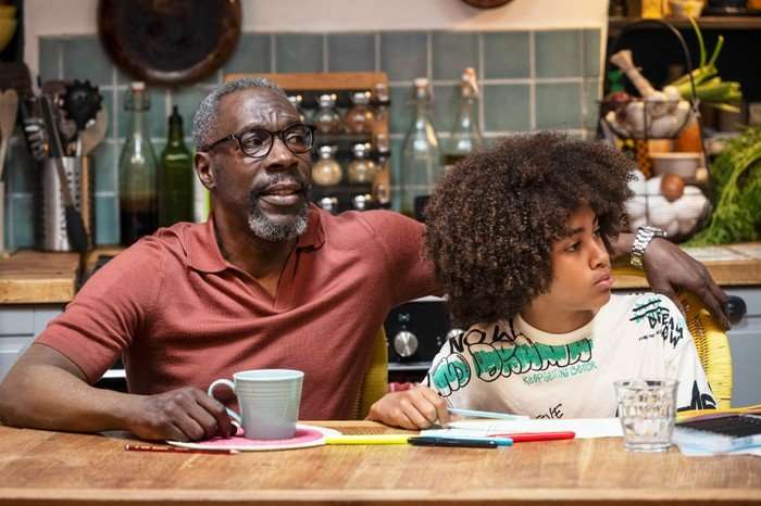 A Good Girl's Guide To Murder Gary Beadle as Victor and Kamari Loyd as Josh, sat the the kitchen table.