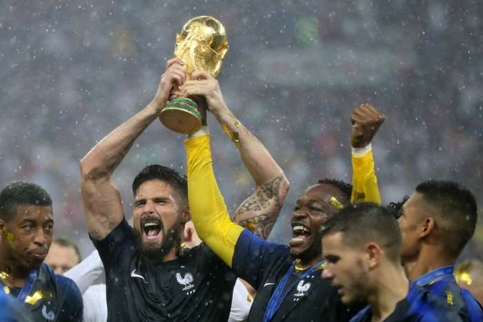 Olivier Giroud France striker Olivier Giround, in blue football kit, holds the World Cup trophy up with his teammates.