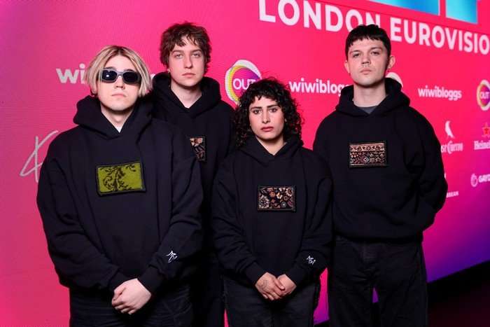 Four people stood in a row wearing matching black hoodies with their hands crossed.