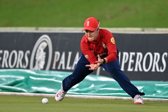 England cricketer Alice Capsey, in red and blue kit, fields a ball on the boundary.