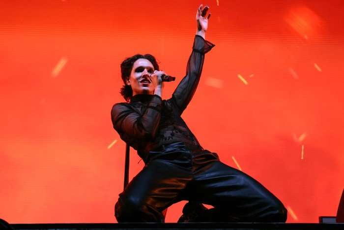 S&oslash;ren Torpegaard Lund knelt on stage singing into a microphone with one arm stretched above him.