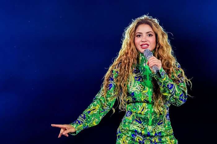 Pop star Shakira, in a green and yellow tracksuit, smiles as she sings on stage in Rio de Janeiro.