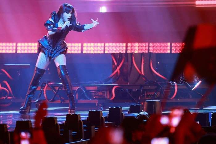 Alexandra Căpitănescu performing on stage as she sings into a microphone with one hand stretched out.