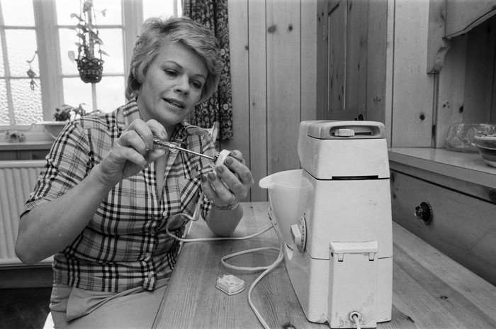 Judith Chalmers Black and white photo of Judith Chalmers fixing a standing mixer with a screwdriver