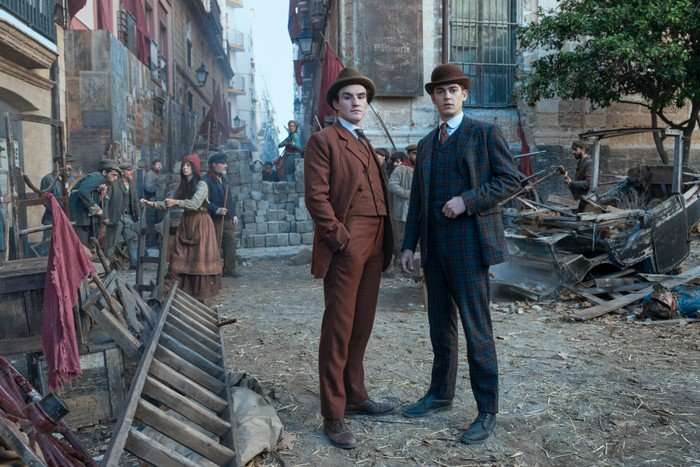 Hero Fiennes Tiffin_Dónal Finn_3 (Photo credit: Dan Smith) Hero Fiennes Tiffin and Dónal Finn in Young Sherlock, stood in a street, wearing suits and hats and surrounded by rubble.
